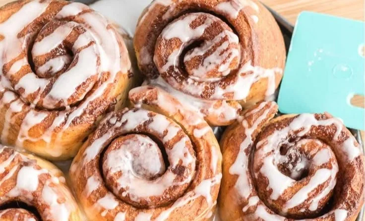 Homemade air fryer cinnamon rolls fresh out of the fryer, topped with icing.