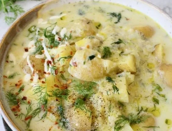 Bowl of chunky potato dill soup garnished with fresh dill and potatoes.
