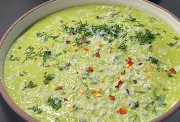 Bowl of high protein low carb broccoli cheese soup garnished with herbs