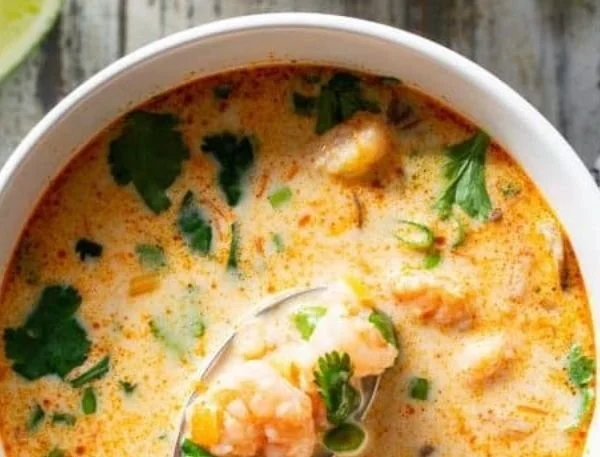 A bowl of Paleo Thai Shrimp Soup garnished with fresh herbs and lime.