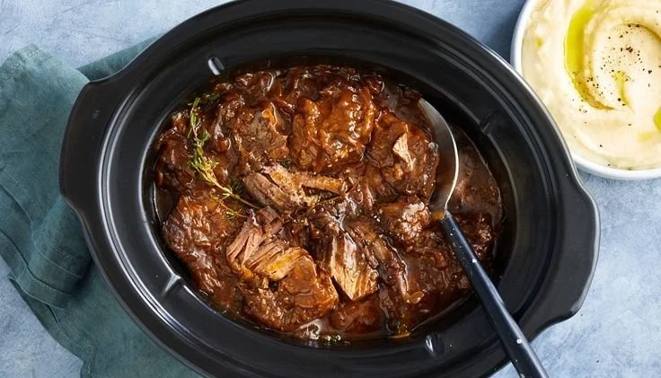 Slow cooker braised steak with onions, showcasing tender meat and rich flavor.
