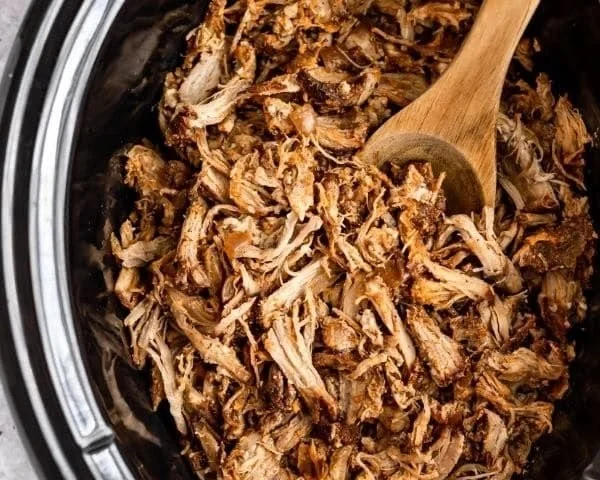 Delicious slow cooker pulled pork served on a platter with BBQ sauce